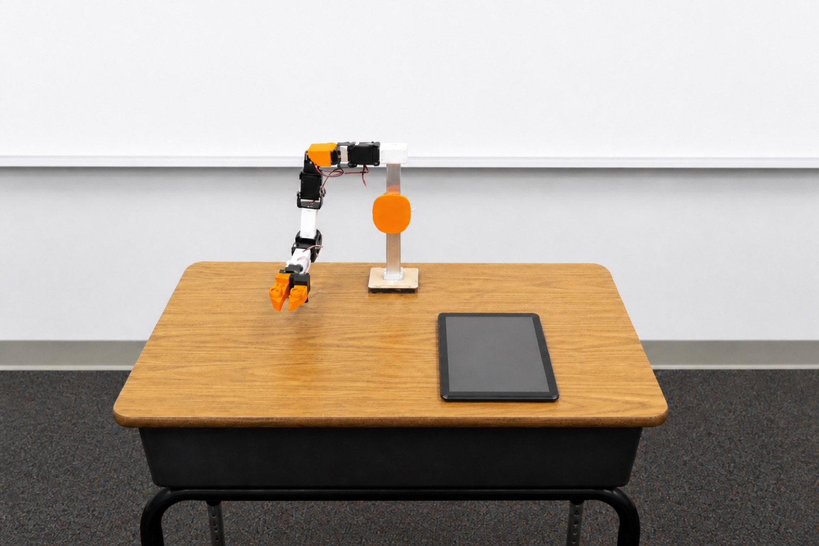 Raven robot arm on a classroom desk with a tablet